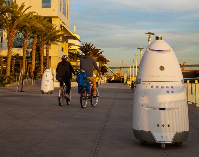 In this April 19, 2016, photo, provided by Stacy Dean Stephens, Knightscope K5 security robots, at right, and background left, patrol alongside a pier, in San Diego. The robots can identify a vehicle parked in a certain location for too long or sense intruders at odd hours. The company expects to have several large mall developers in California start using the robots in late 2016. (Stacy Dean Stephens via AP)